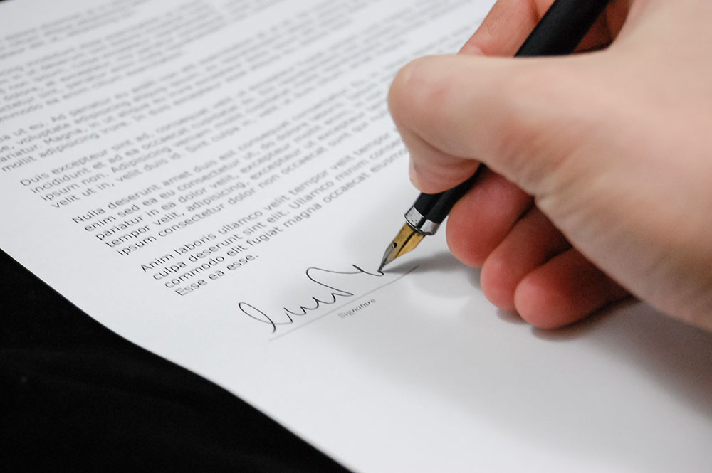 hand signing a paper with a pen